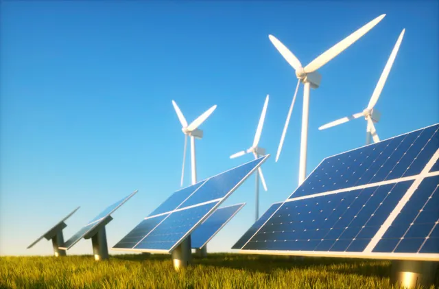 Zonnepanelen en windturbines in een weiland onder een heldere hemel